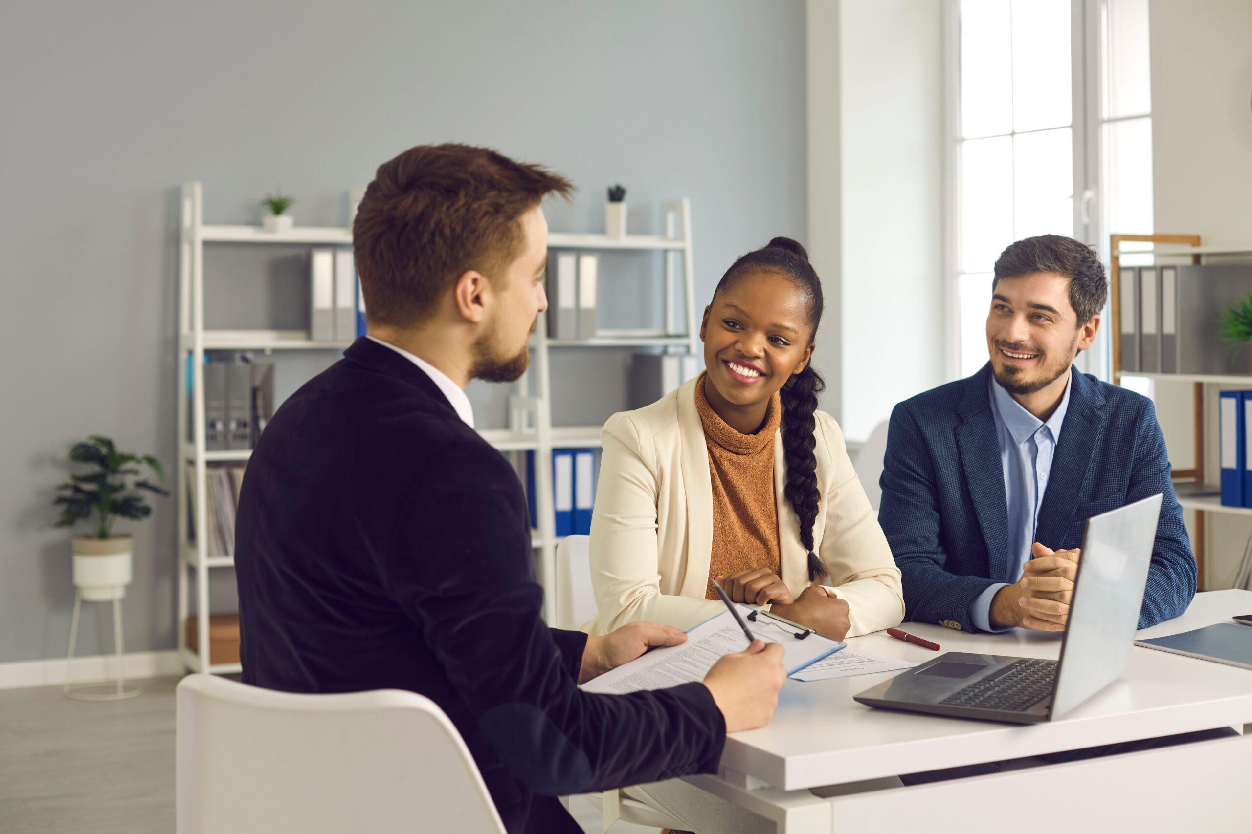 Financial manager, realtor or insurer consulting clients, interviewing interracial couple in office. Happy smiling black wife and caucasian husband taking loan, mortgage, purchasing real estate
